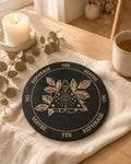 Black pendulum board with eye and leaves design on linen with candle